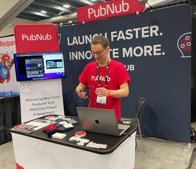 Oliver, a PubNub employee wearing a PubNub T-shirt in front of the PubNub booth at GDC 2024